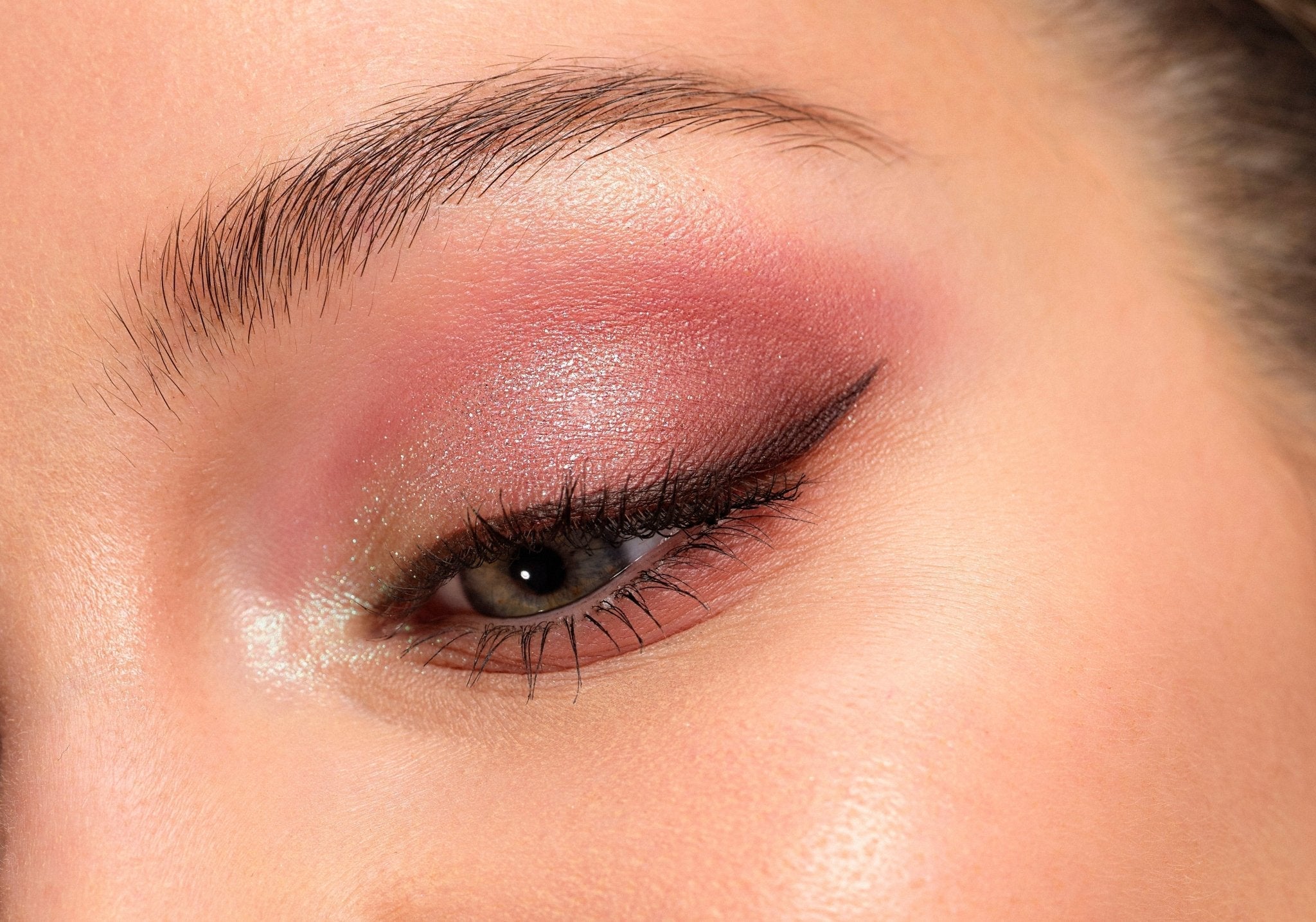 Gros plan sur œil maquillé avec fard à paupières rose et trait d'eyeliner noir pour un maquillage de jour
