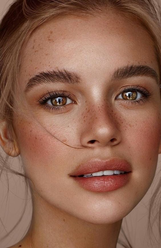 Portrait rapproché d'une femme lumineuse avec teint naturel, peau nette, blush subtil et regard éclatant