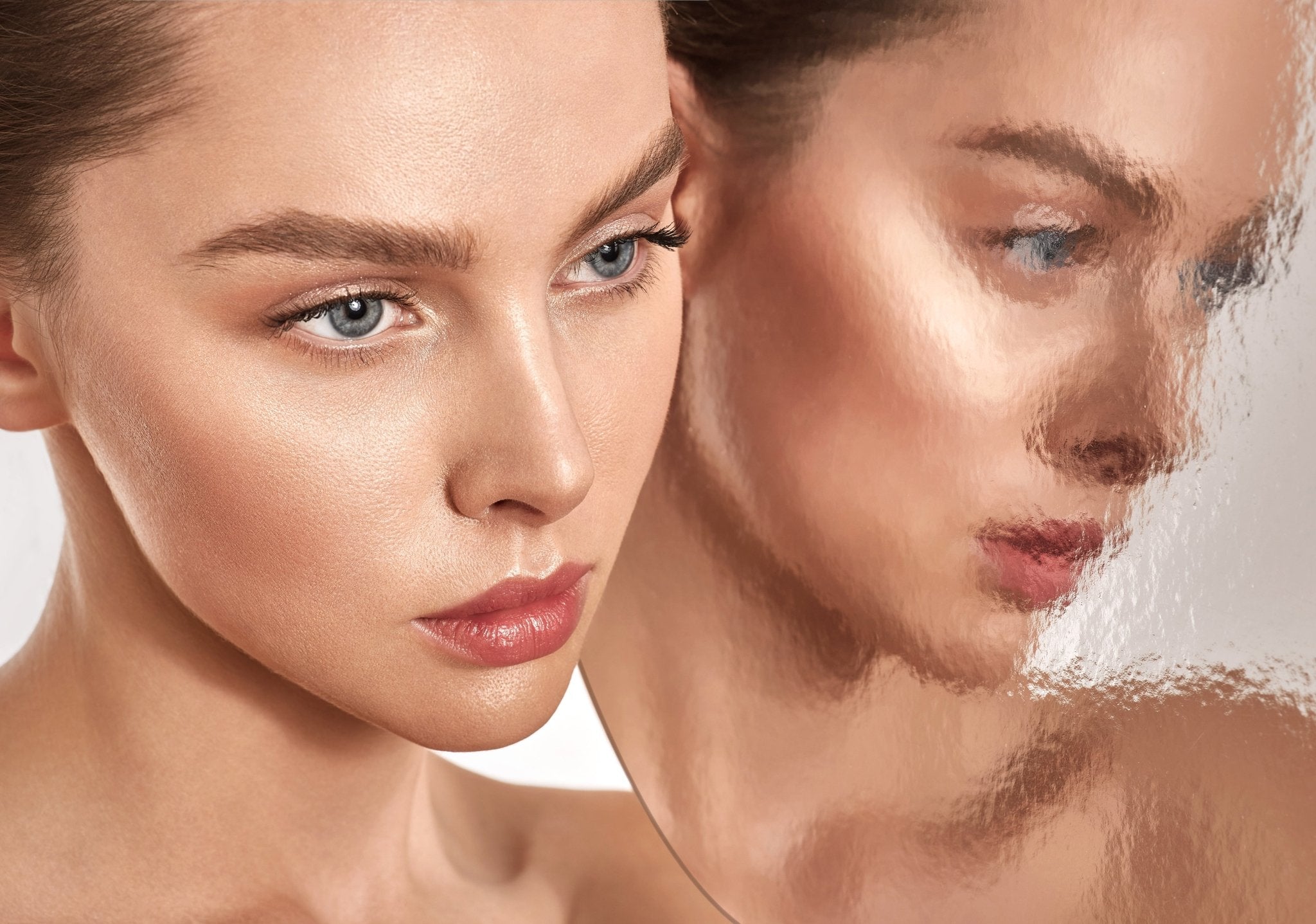 Femme au teint lumineux et naturel se regardant dans un miroir flou, soins beauté vegan